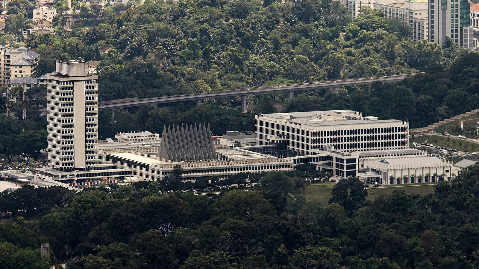 吉隆坡马来西亚国会大厦建筑群远景，周围为绿树环绕