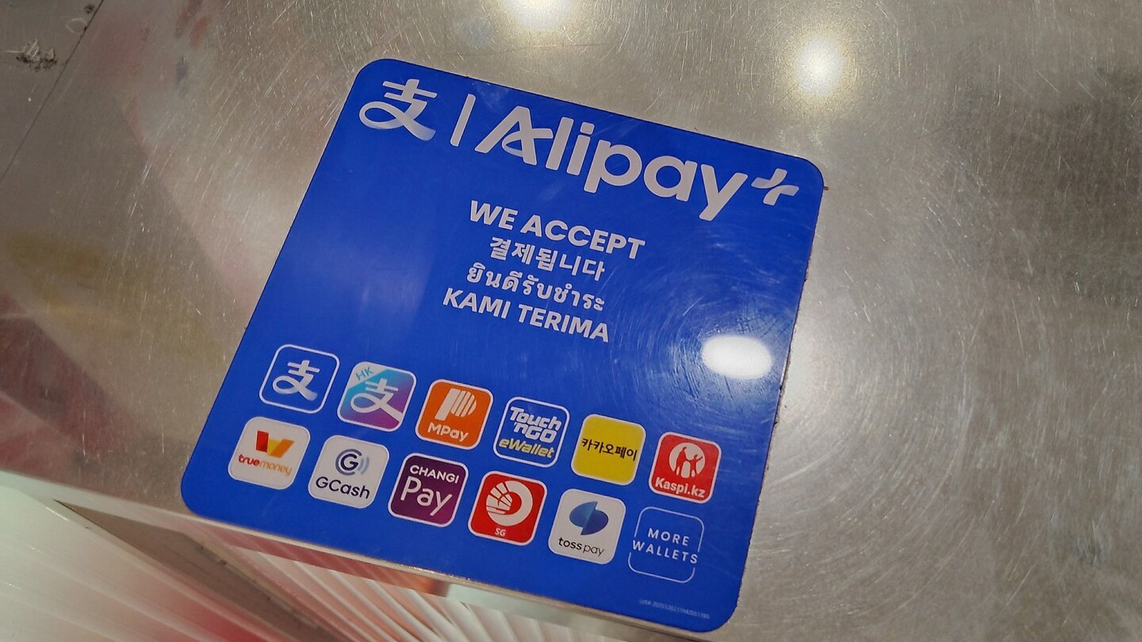 中国苏州一家饮品店柜台上的Alipay+收款贴纸，列出可接受的多国电子钱包
